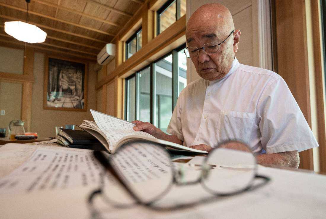 This photo taken on Sept. 5 shows chief Buddhist priest Eiichi Shinohara looking at a diary of a woman who was swindled out of millions of yen, during an interview with AFP at his temple near the city of Narita, Chiba prefecture.