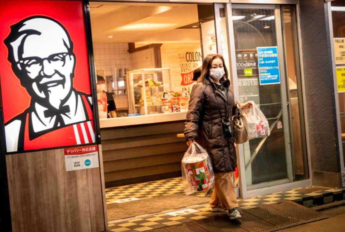 A woman holding Christmas meal boxes leaves a KFC restaurant on Christmas Eve in Tokyo on Dec. 24, 2022. Forget turkey, stuffing and Brussels sprouts — in Japan, the most popular food to eat at Christmas is an American fast-food favorite: KFC. 