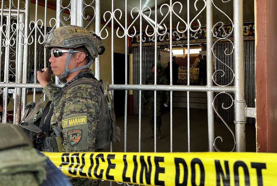 Military personnel stand guard at the entrance of a gymnasium while police investigators look for evidence after a bomb attack at Mindanao State University in Marawi, Lanao del sur province on December 3, 2023.