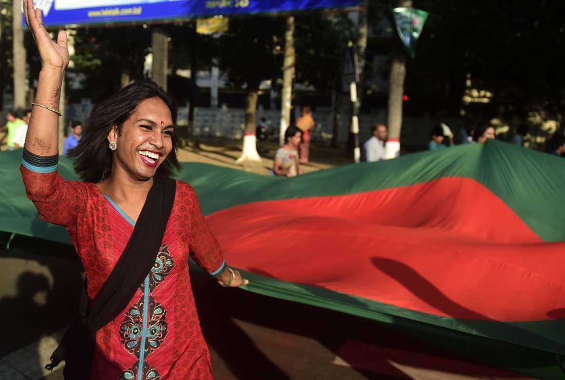  A transgender person marches on a street in Bangladesh holding the national flag.