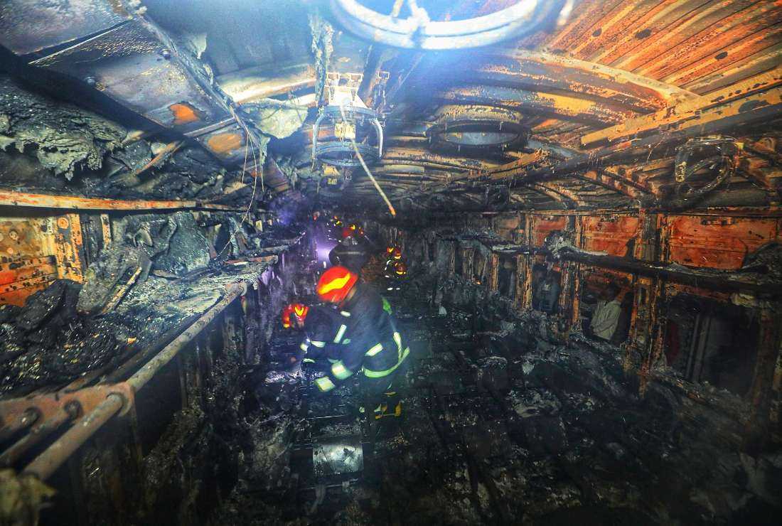 Bangladeshi fire fighters search through a burnt out carriage of the Benapole Express in Dhaka on Jan. 5.