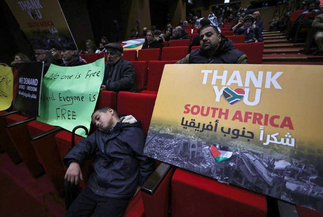 Palestinians lift placards as they attend a live projection of the International Court of Justice (ICJ) hearing of the case brought by South Africa against Israel, at the Ramallah municipality in the occupied West Bank on Jan. 26. 
