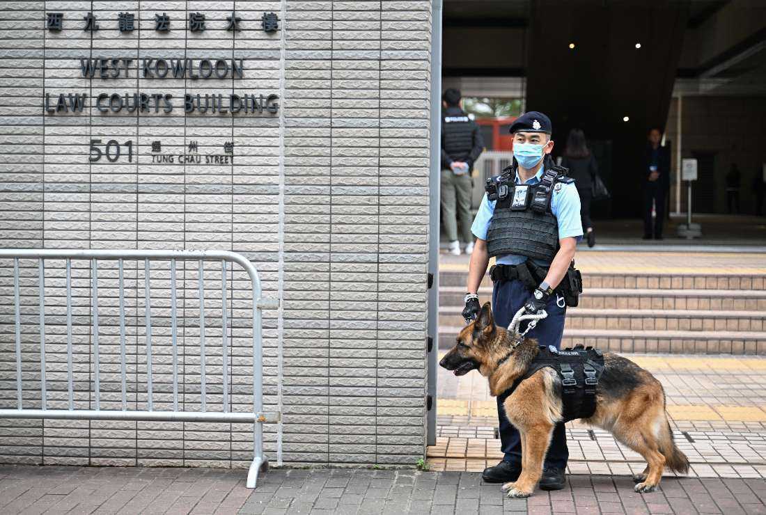 A police dog and its handler stand outside the entrance to the West Kowloon court for the opening day of the trial of pro-democracy media tycoon Jimmy Lai in Hong Kong on Dec. 18, 2023.