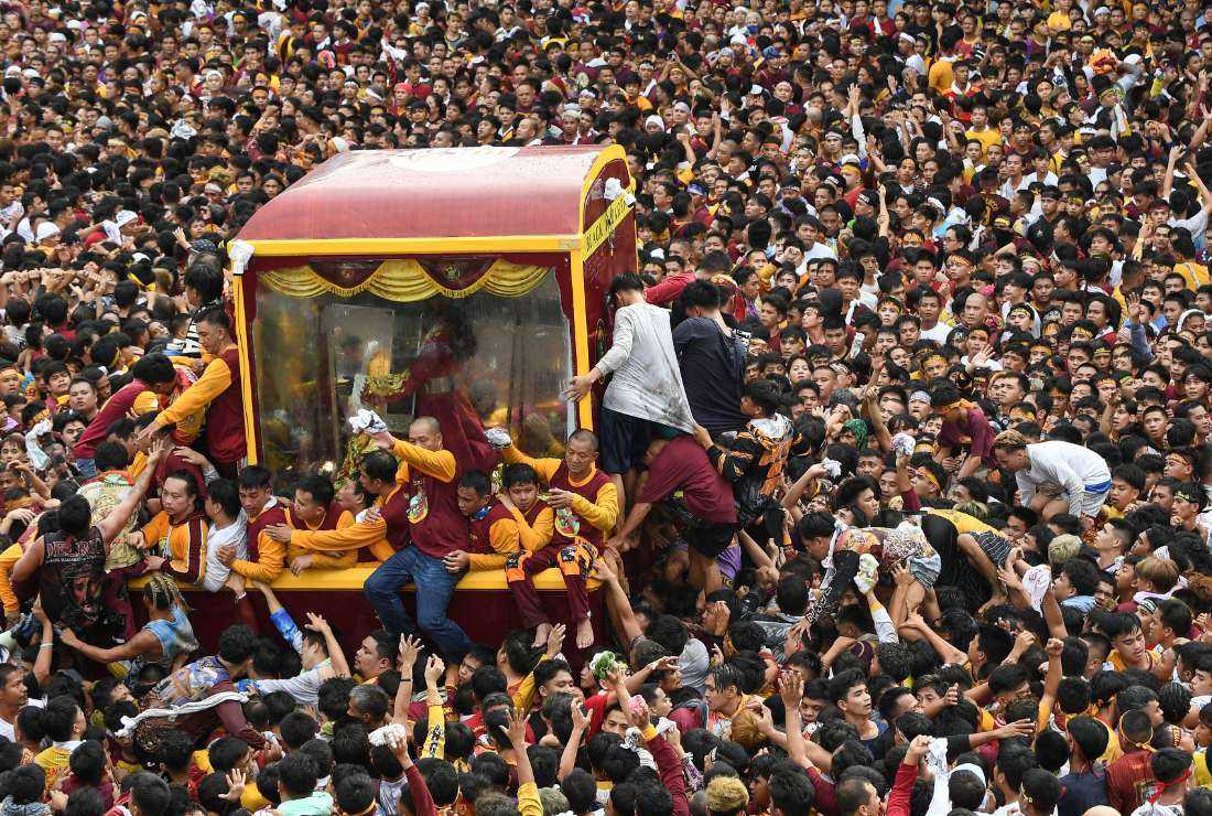 Catholic devotees climb into a glass-covered carriage carrying the so-called Black Nazarene statue as they try to touch it during an annual religious procession in Manila on Jan. 9. 