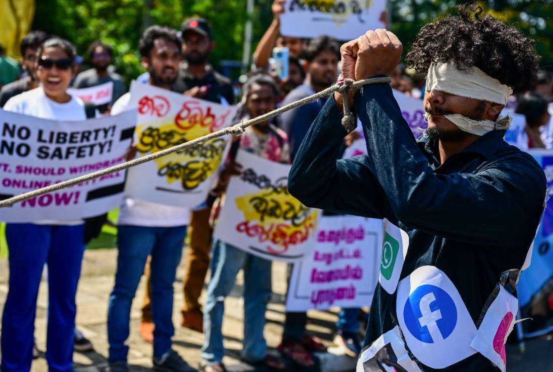 A blindfolded activist with a rope tied around his wrists and covered with logos of different social media platforms takes part in a protest against the proposed 'Online Safety Bill', near the parliament building in Colombo on Jan. 24. Sri Lanka's parliament passed the social media regulation bill dubbed 'draconian' by the opposition, which could make companies criminally liable for posts authorities deem harmful.