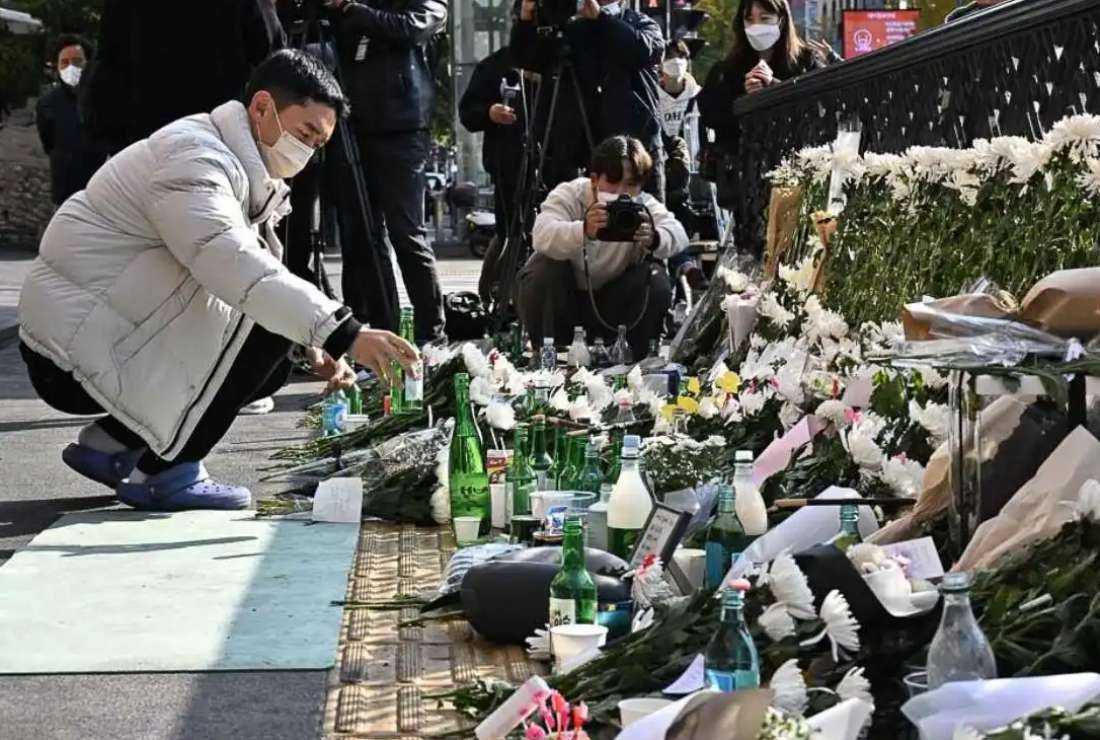 A man offers an alcoholic beverage to pay tribute to those who perished during the Halloween stampede, at a makeshift memorial outside the Itaewon subway station in Seoul on Oct. 31, 2022.