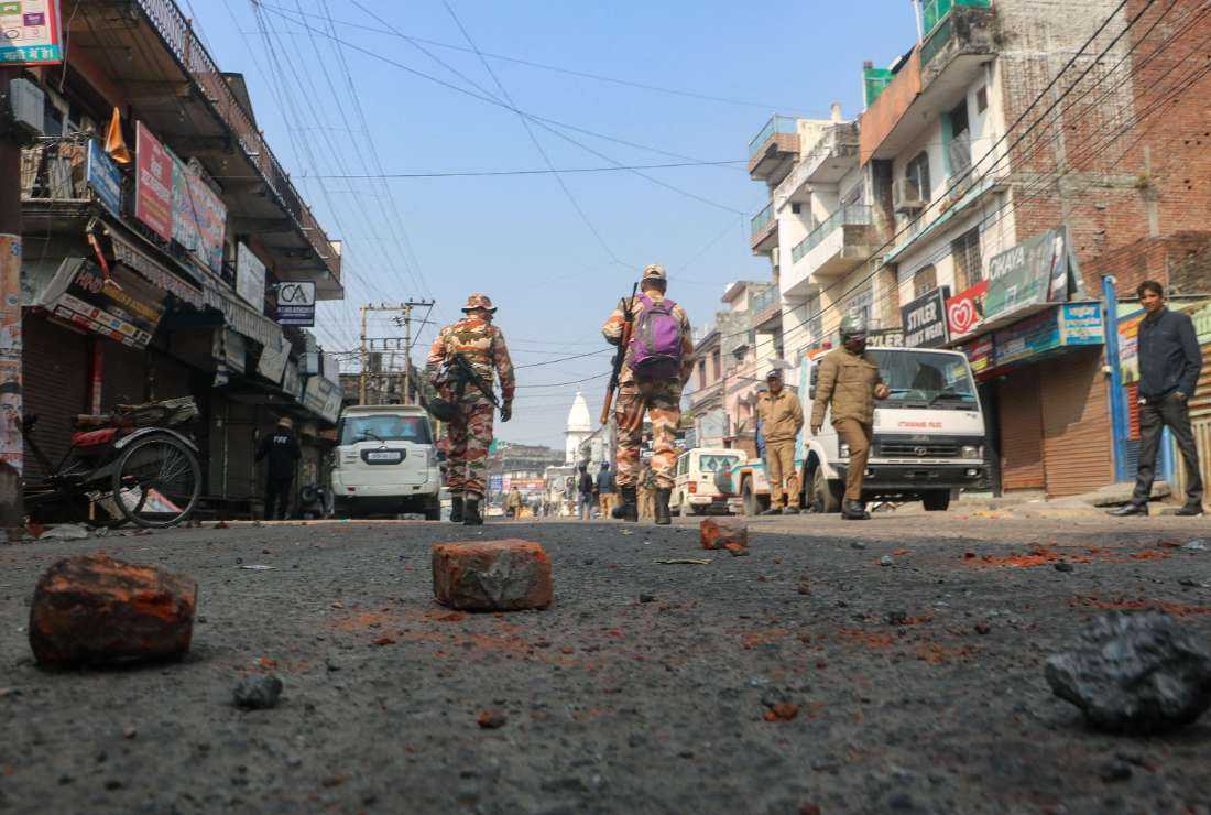 Security personnel walk past bricks and stones scattered on a road, a day after the religious clashes sparked following the destruction of a madrassa (an Islamic school) in Haldwani district of the northern state of Uttarakhand on Feb. 9.