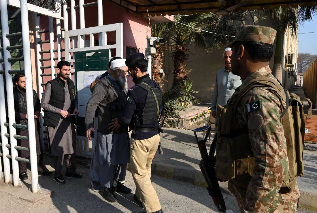 A policeman frisks an election presiding officer at a distribution center of polling material in Peshawar on Feb. 7, a day prior to Pakistan's national elections.