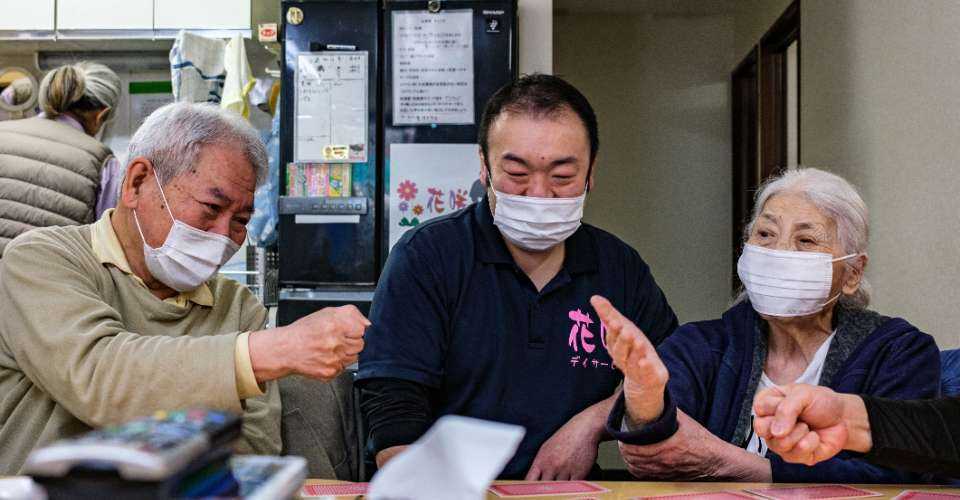 A staff member with elderly people at the Hanasaki daycare center in Tokyo on March 30, 2022.