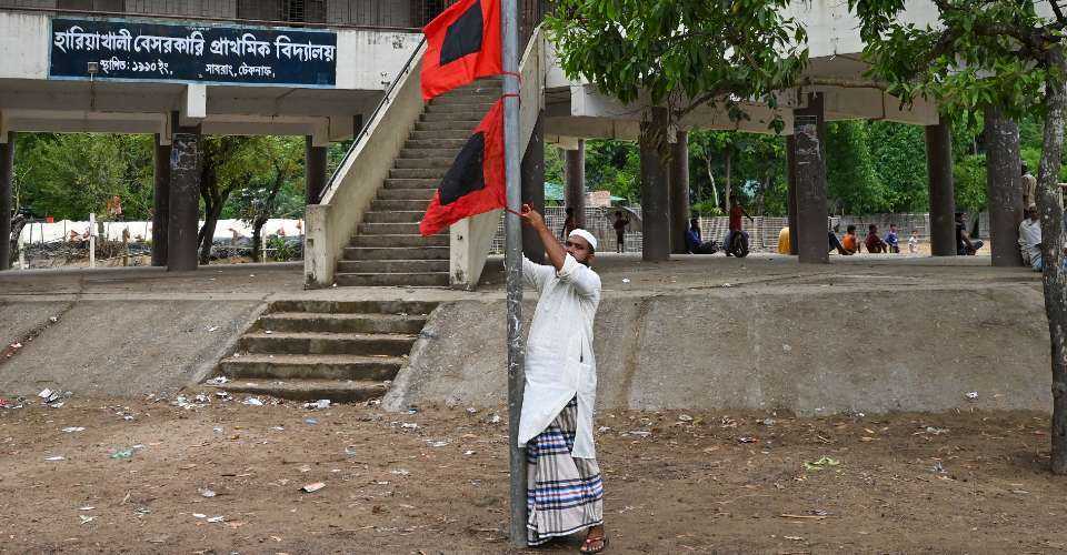 A man raises a storm danger signal flag ahead of Cyclone Mocha's landfall in Bangladesh on May 13, 2023.  The South Asian nation lacks a warning mechanism for pre-monsoon storms called nor’westers