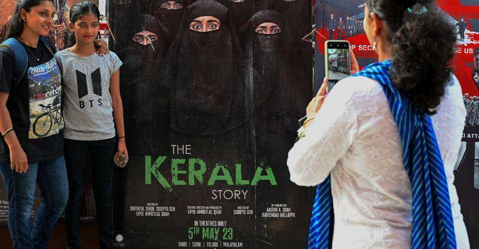 Moviegoers pose for a picture next to the poster of the film - The Kerala Story - at a theater in Mumbai on May 10, 2023. 
