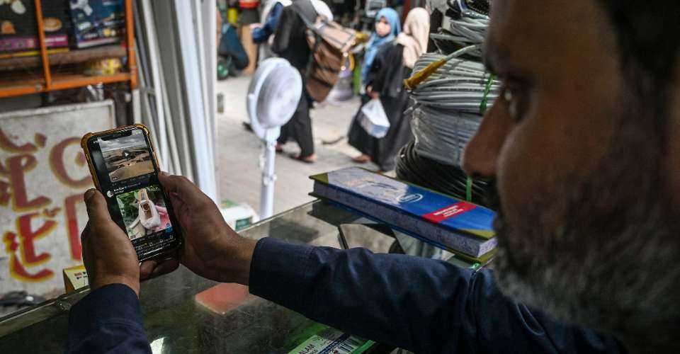 A man uses the social media platform X, formerly known as Twitter, on his phone at a market in Islamabad on April 17.