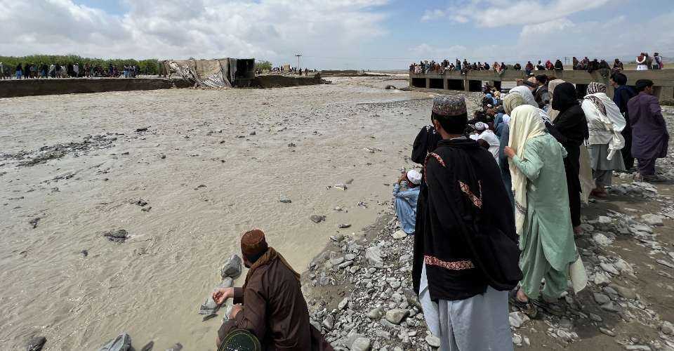 Residents gather beside a collapsed bridge due to flood waters following heavy rains in Pishin district on April 15.
