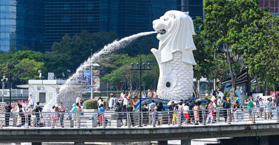People gather for a photograph next to the Merlion statue at Marina Bay waterfront in Singapore on March 18, 2024.