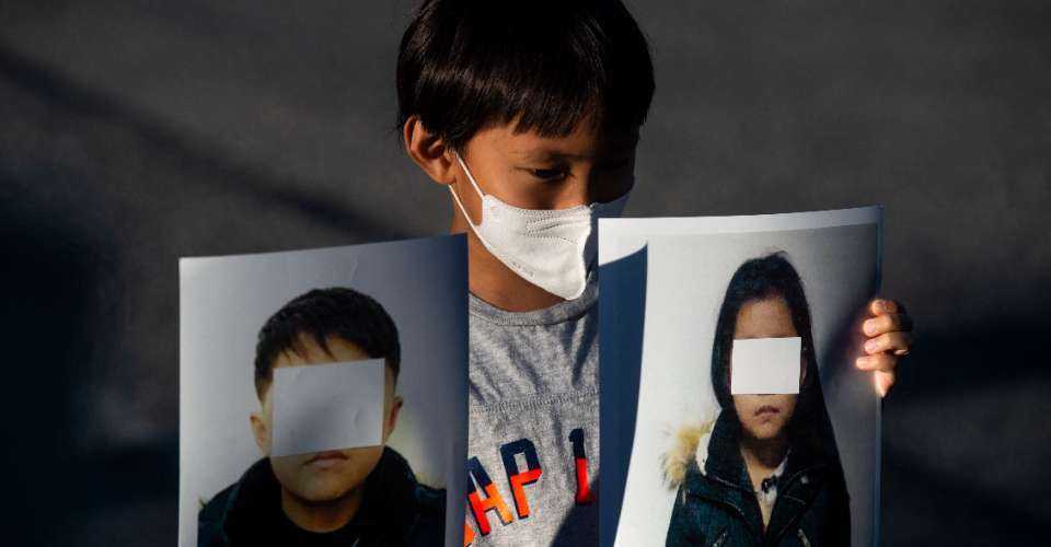 A young boy holds pictures of alleged young North Korean refugees during a demonstration calling on Chinese President Xi Jinping to allow safe passage to North Koreans detained in China across the street from the Chinese embassy in Washington on Sept. 24, 2021.