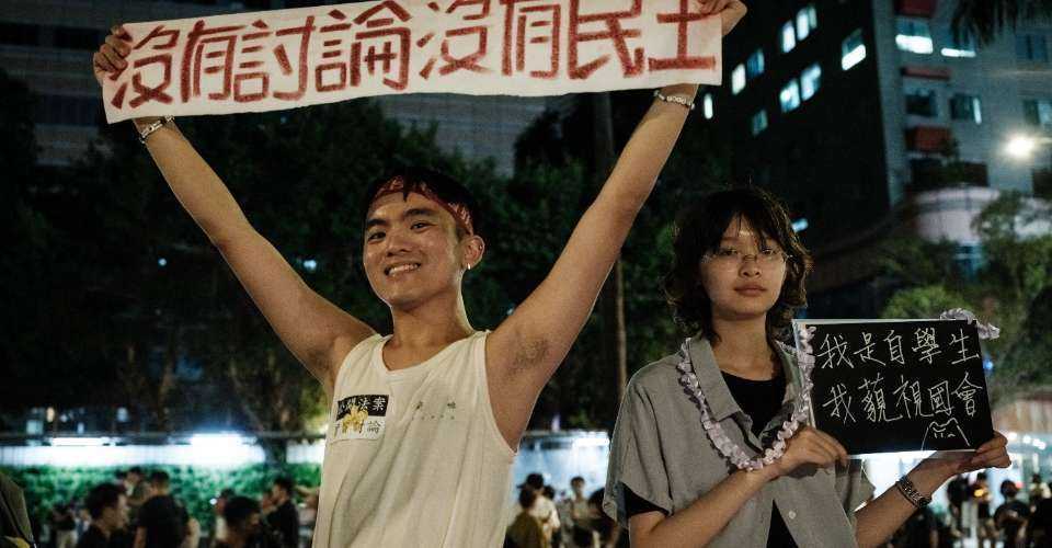 A demonstrator (left) holds a banner reading 'No discussion, no democracy' as they occupy a road in protest against plans by the main opposition Kuomintang (KMT) and the Taiwan People's Party (TPP) to expand the parliamentary powers during the vote for the Parliament reform bill, outside the Parliament in Taipei on May 24.