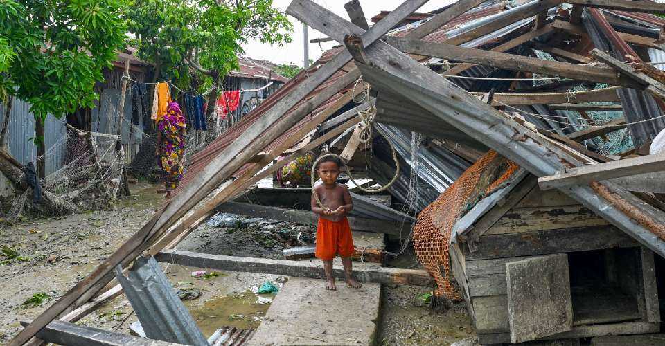 A child stands at his damaged house after cyclone Remal's landfall in Patuakhali on May 28, 2024. Cyclone Remal, which made landfall in low-lying Bangladesh and neighbouring India on May 26 evening with fierce gales and crashing waves, left at least 21 people dead, destroyed thousands of homes, smashed seawalls and flooded cities across the two countries.