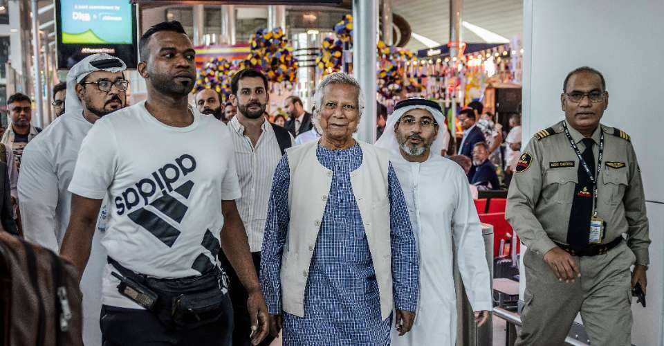 Nobel laureate Muhammad Yunus (center) is escorted by Emirati security personnel as he walks through Dubai International Airport before boarding a flight to Dhaka, in Dubai on Aug. 8. Yunus is expected to lead a caretaker government after a student-led uprising ended the 15-year rule of Sheikh Hasina.