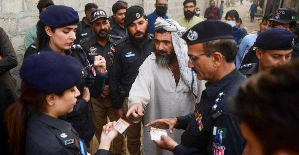 Police personnel check documents of Afghan refugees during a search operation to identify alleged illegal immigrants, on the outskirts of Karachi on Nov. 17, 2023.