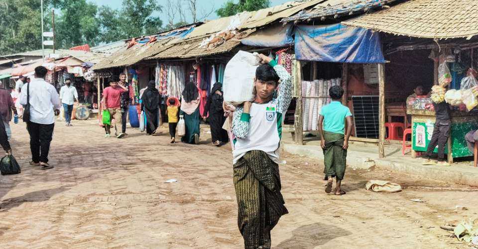 A Rohingya refugee carrying a sack walks across a market at the Kutupalong refugee camp in Ukhia, Bangladesh on Jan 12. Refugees who escaped Myanmar nearly a decade ago await developments more than 8,000 kilometers (5,000 miles) away at the International Court of Justice (ICJ) in The Hague, where a genocide case against Myanmar opened on Jan 12
